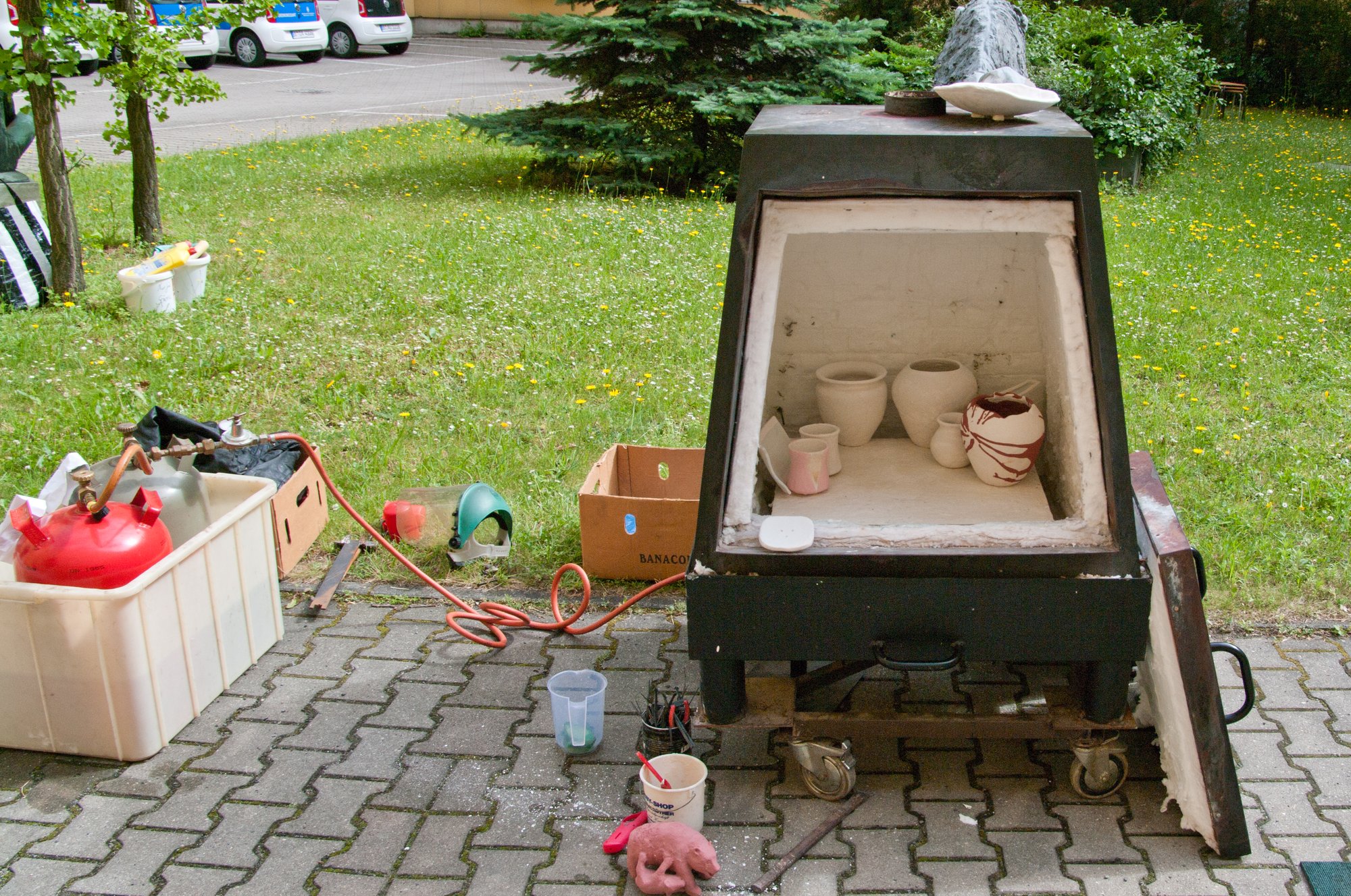 Cuisson raku en plein air, le ceramiste sort une piece incandescente du four avec des pinces